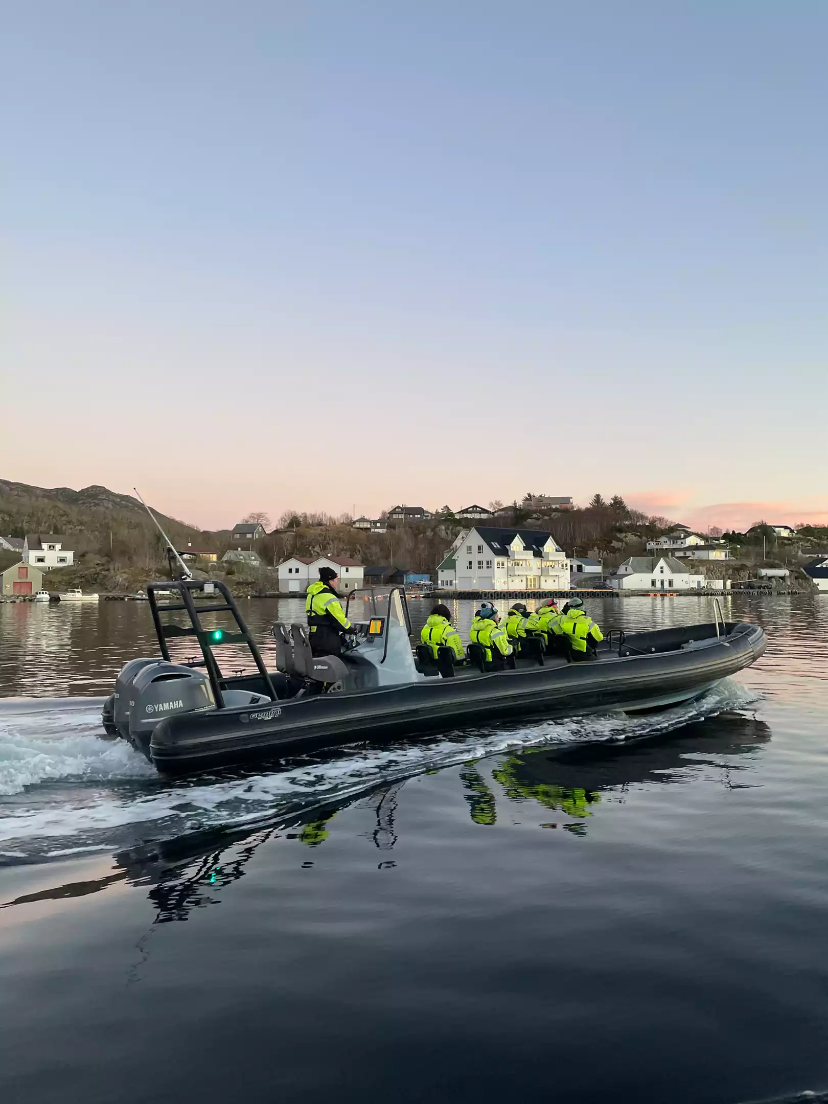 RIB-båt med passasjerer på rolig sjø i Bergen ved solnedgang